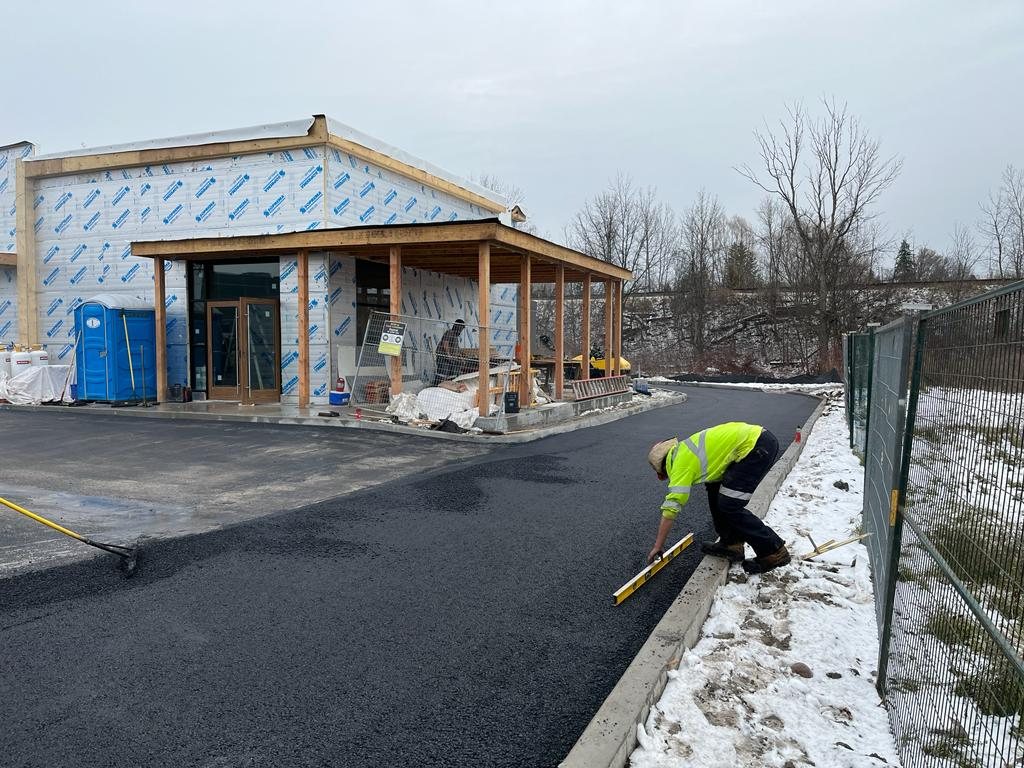 Genesis team member measuring level of newly laid asphalt at a commercial business