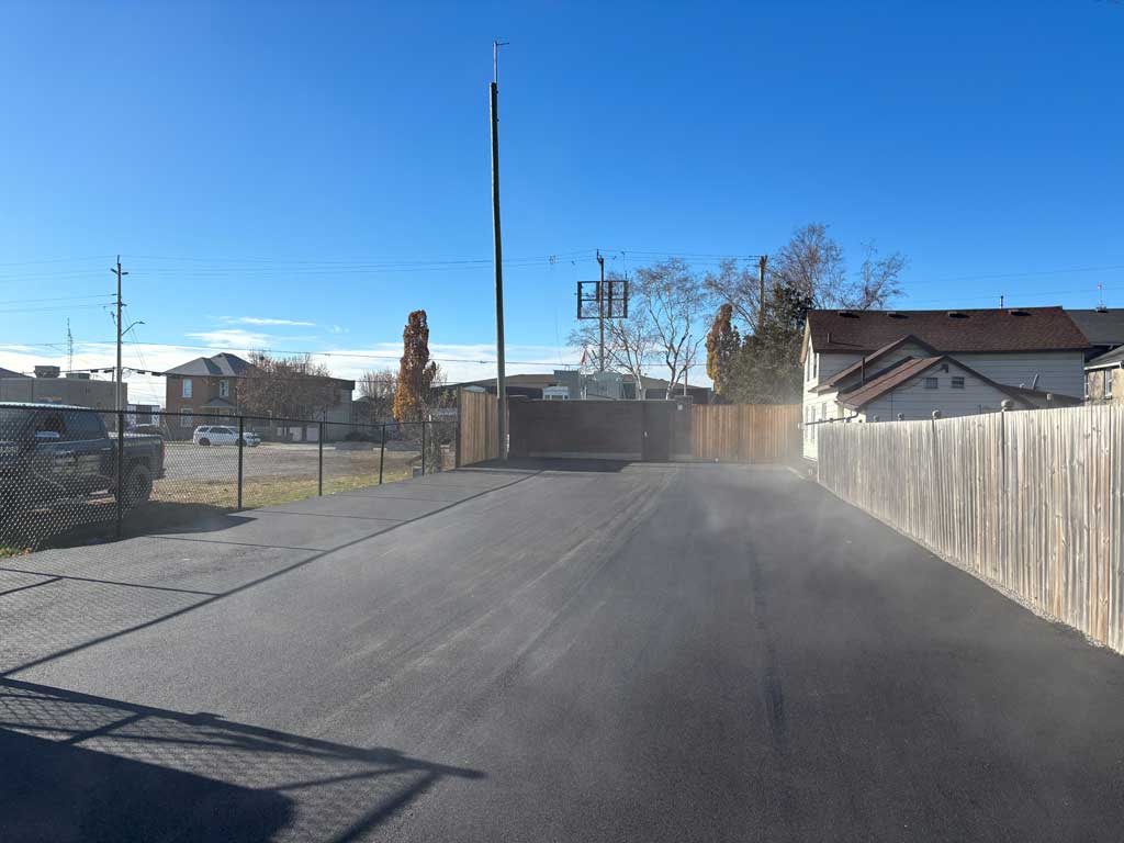 Completed Elexicon Commercial Paving Project, between a wooden fence and chain link