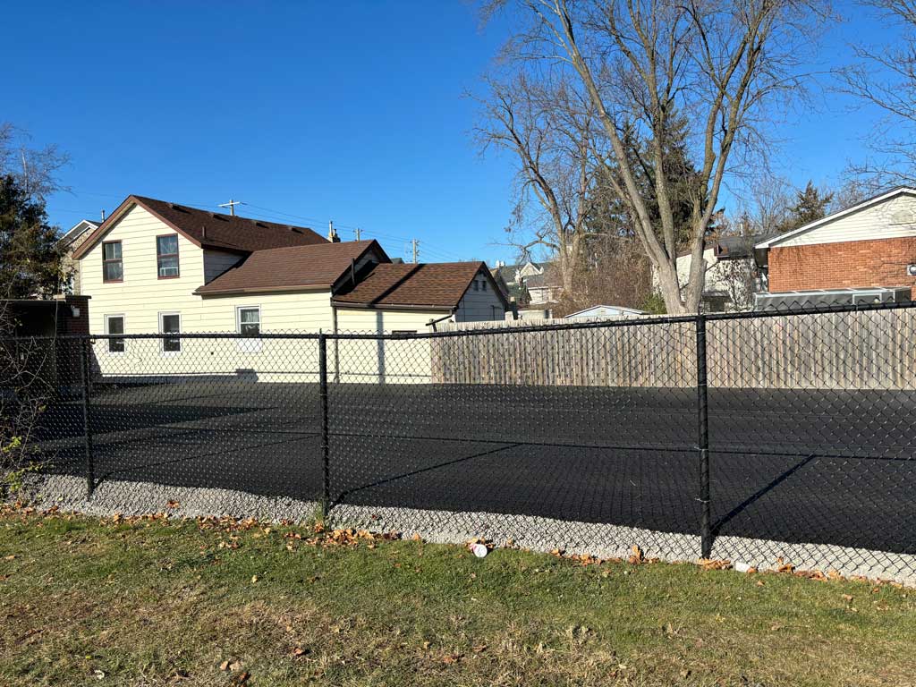 Finished commercial paving project behind chain link fence